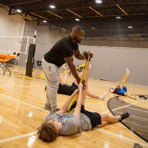 Andre stretching youth athlete on gym floor